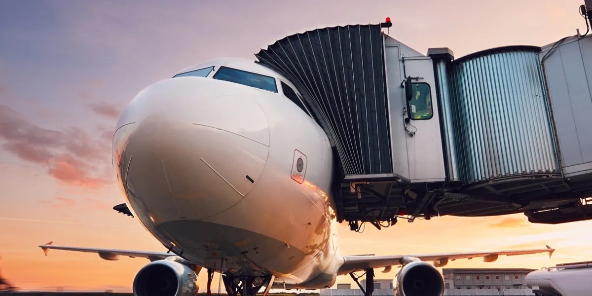 A commercial airplane connected to a jet bridge at the airport gate illustrates efficient resource management for aircraft turnaround and passenger boarding.